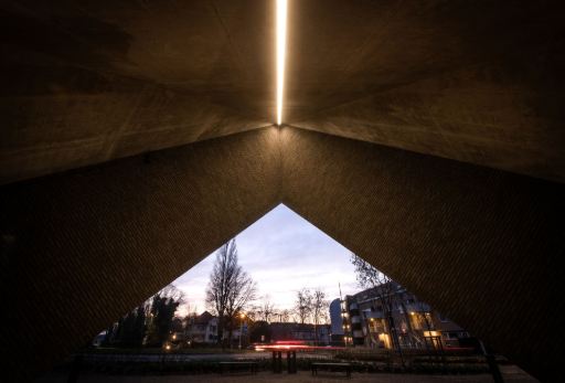 Architecturale verlichting met verticale lichtlijn in een monumentaal betonnen gebouw bij schemering